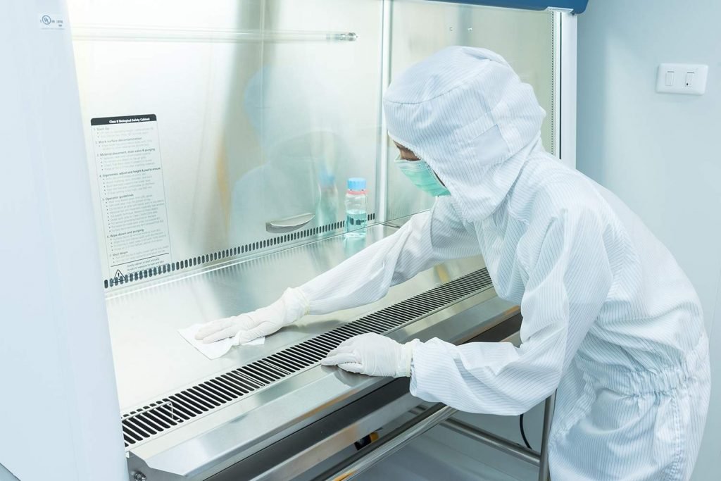a scientist in sterile coverall gown using alcohol 70% and cleanroom wiper for cleaning biological safety cabinet (bsc)