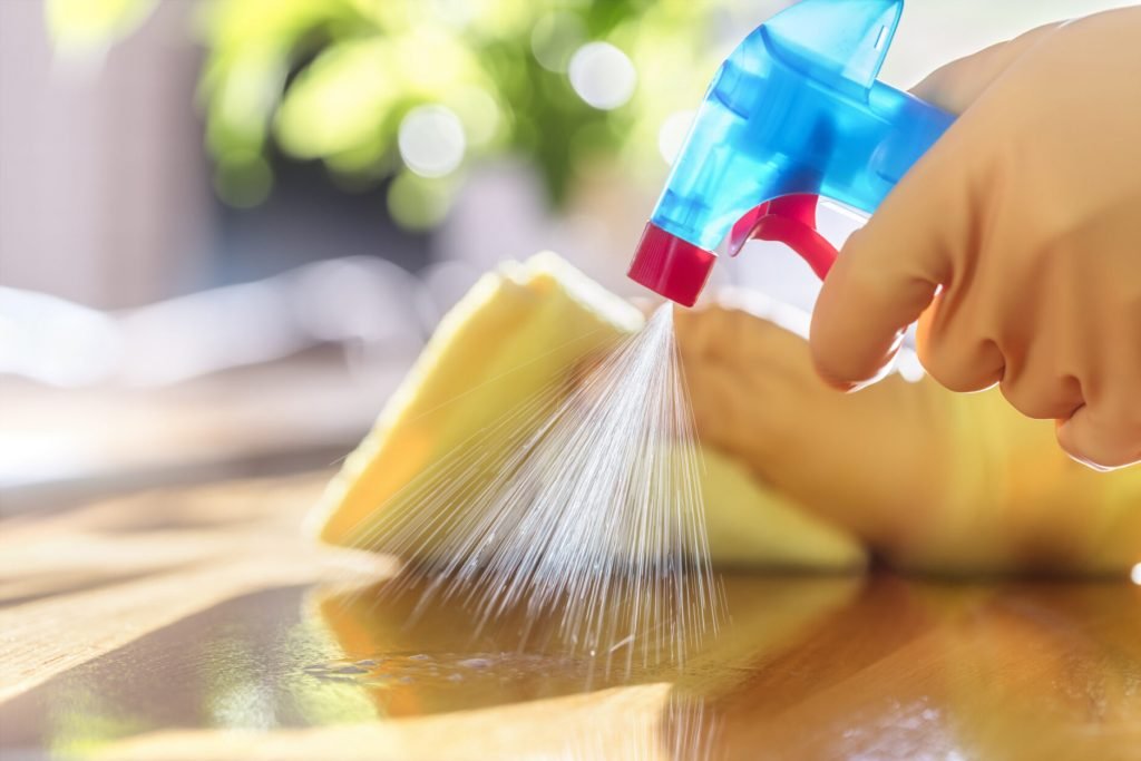 cleaning with spray detergent, rubber gloves and dish cloth on work surface