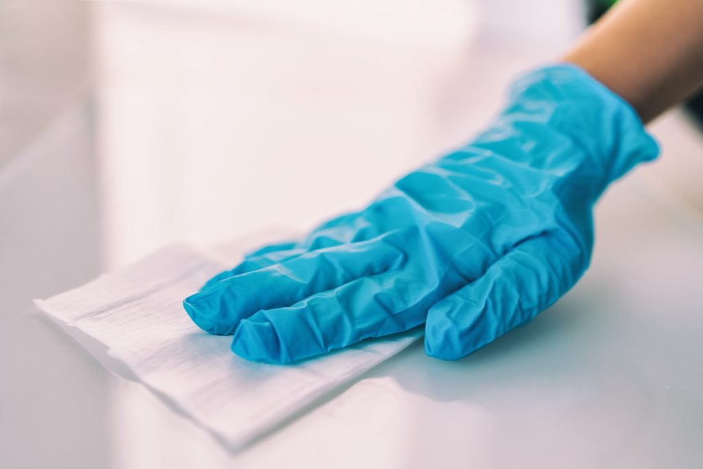 surface disinfecting home cleaning with sanitizing antibacterial wipes protection against covid 19 spreading wearing medical blue gloves. sanitize surfaces prevention in hospitals and public spaces