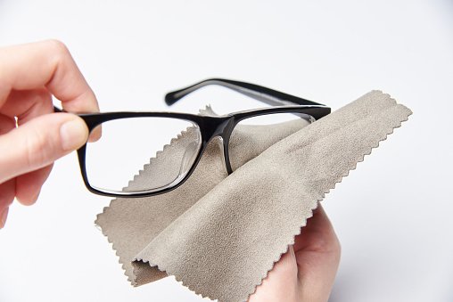 the hands are rubbing the glasses for a view with a napkin